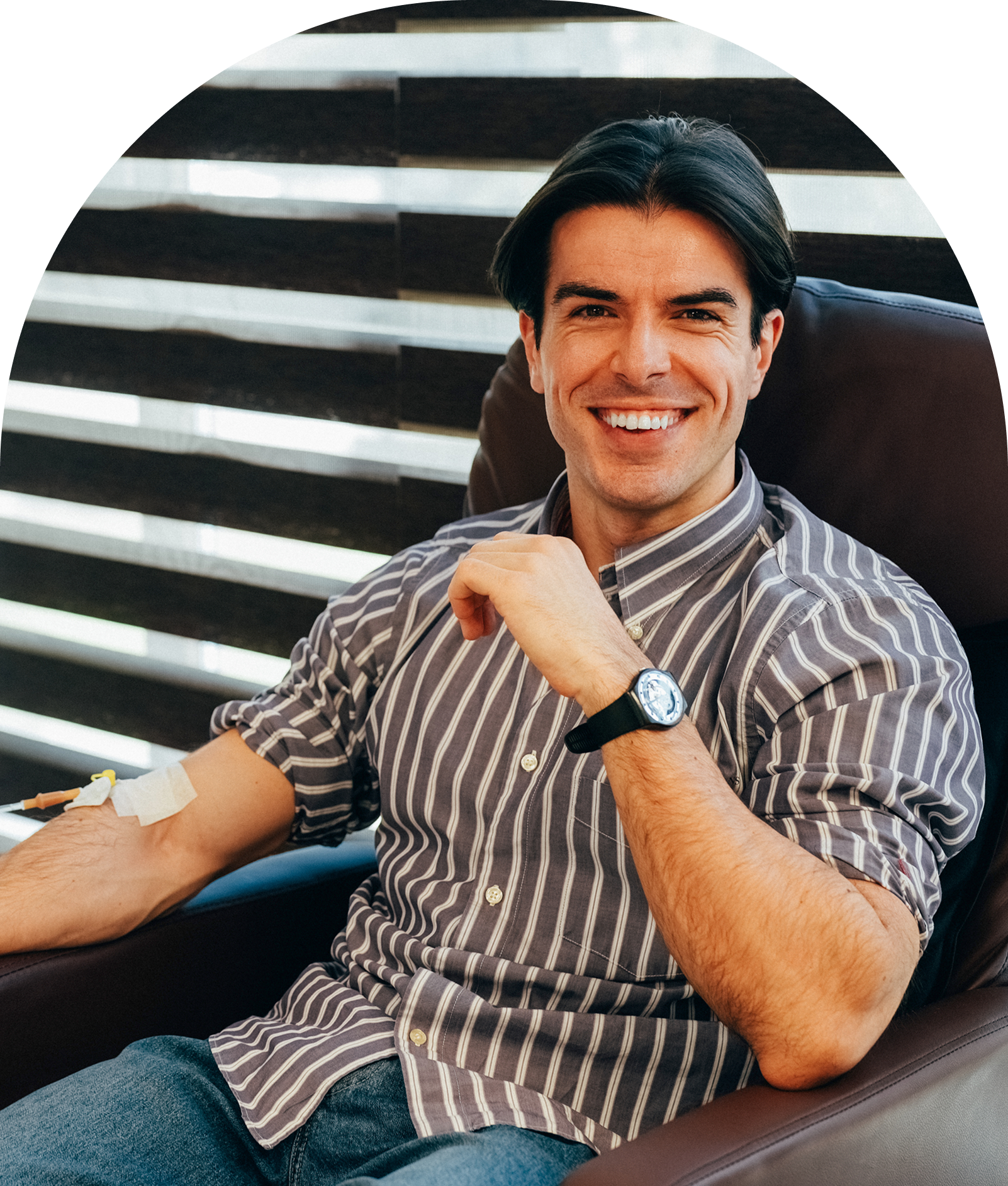 Man smiling while donating blood in chair.