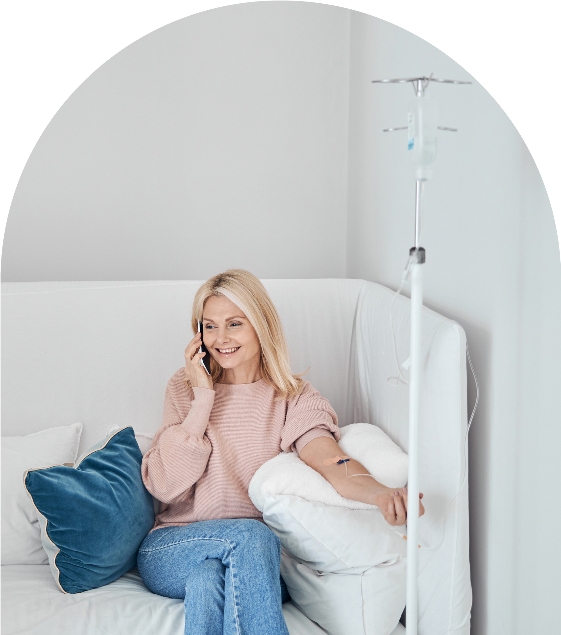 Woman on sofa with IV drip smiling.
